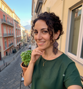 Femme souriante sur un balcon à Naples portant les boucles d'oreilles artisanales roses et noires, avec une vue typique sur une ruelle italienne en arrière-plan.