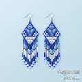 Photographie professionnelle sur fond bleu pâle des boucles d'oreilles Artisanat Zenka en perles de rocaille avec motifs losanges et franges.