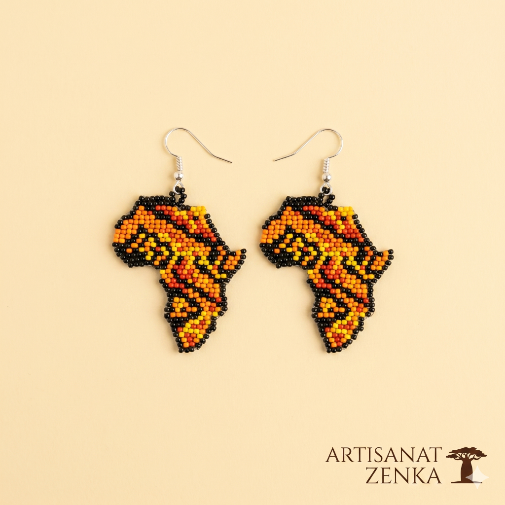 Paire de boucles d'oreilles artisanales en perles de rocaille aux couleurs chaudes (orange, rouge, jaune, noir) en forme de carte d'Afrique, disposées sur un fond jaune pâle avec le logo Artisanat Zenka.