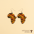 Paire de boucles d'oreilles artisanales en perles de rocaille aux couleurs chaudes (orange, rouge, jaune, noir) en forme de carte d'Afrique, disposées sur un fond jaune pâle avec le logo Artisanat Zenka.