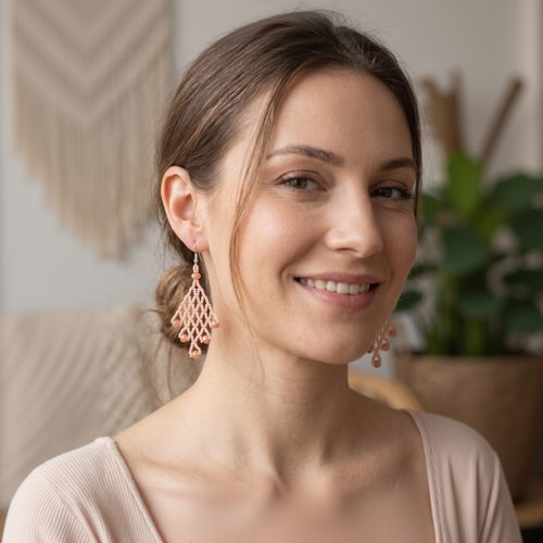 Gros plan d'une femme souriante portant des boucles d'oreilles pendantes en perles roses de style losange, Artisanat Zenka.