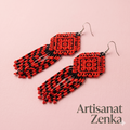 Vue rapprochée professionnelle des boucles d'oreilles en perles rouges et noires sur un fond rose texturé, avec l'inscription Artisanat Zenka.