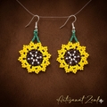 Vue de face professionnelle de boucles d'oreilles artisanales en perles jaunes, marron et vertes en forme de tournesol sur un fond texturé marron avec la signature dorée Artisanat Zenka.