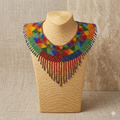 Collier plastron en perles multicolores de la collection Zenka exposé sur un buste de présentation beige avec un fond texturé élégant et neutre.