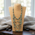 Image de produit professionnelle du collier sur buste avec fond flou lumineux, galets décoratifs et signature Artisanat Zenka.