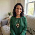 Femme souriante portant un collier tournesol artisanal lors d'un repas de famille chaleureux, mettant en valeur le style universel et culturel des Ateliers Beccar.