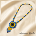 Vue de dessus du collier perlé tournesol bleu et jaune sur un fond de soie crème avec la signature Artisanat Zenka.