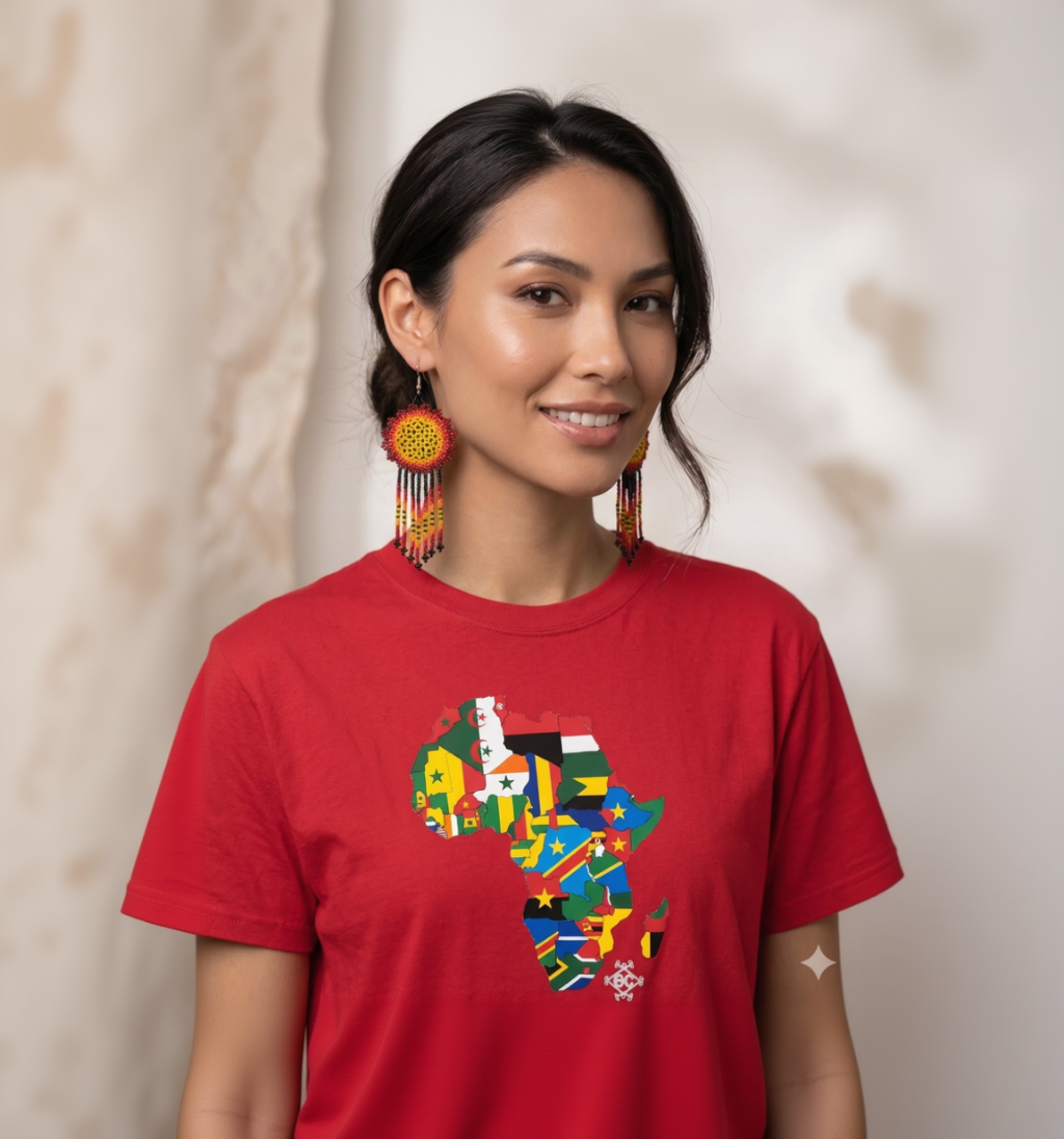 Femme souriante portant de grandes boucles d'oreilles artisanales en perles et un t-shirt rouge avec la carte de l'Afrique en drapeaux colorés.