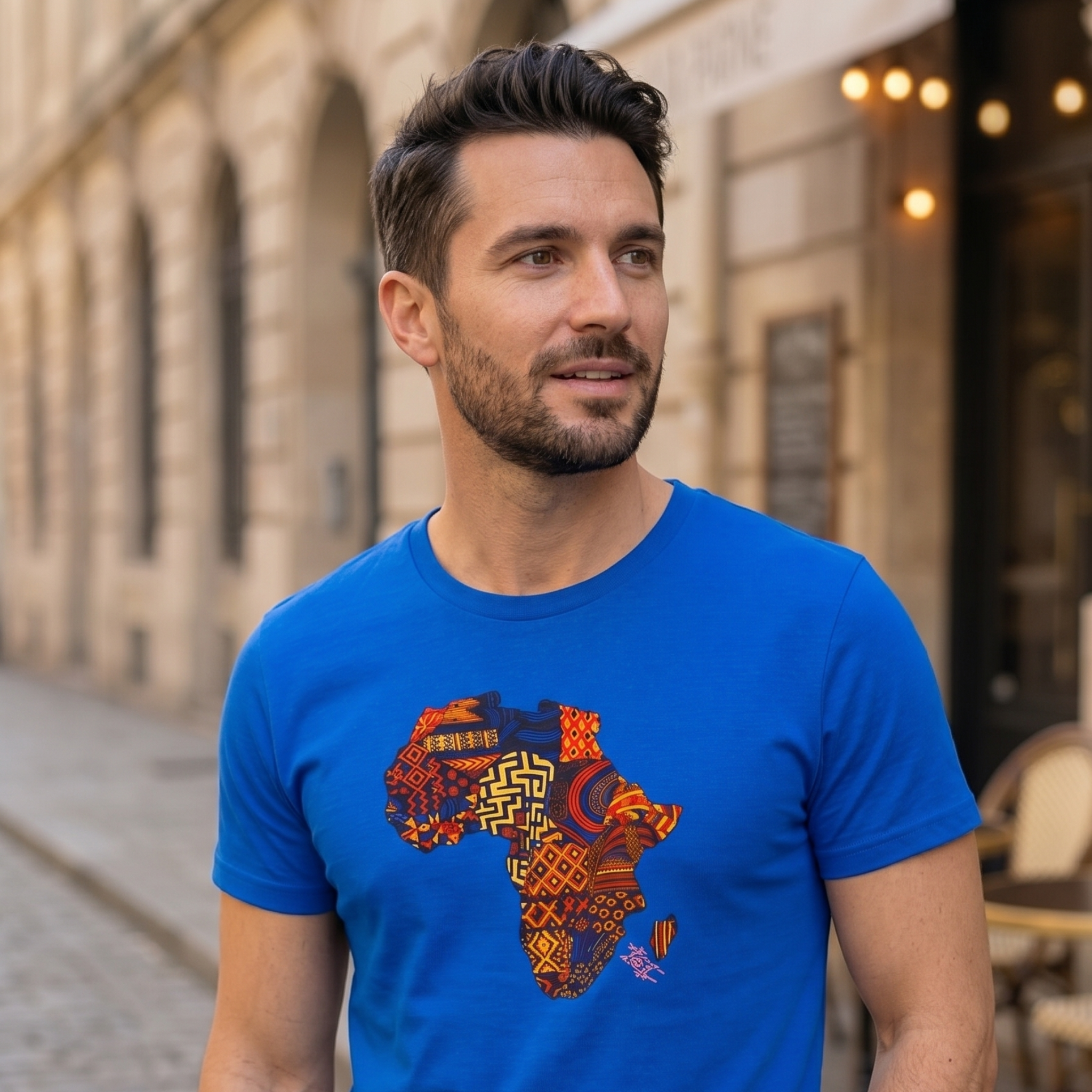 Homme en t-shirt bleu électrique avec imprimé géographique africain multicolore, style décontracté.