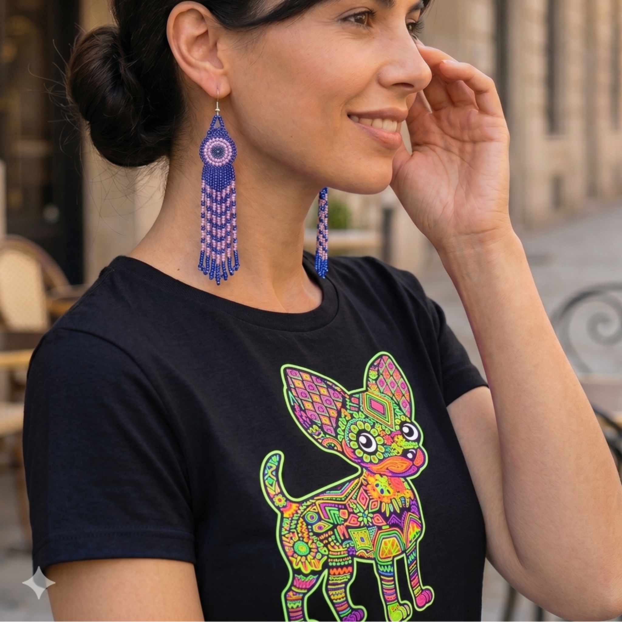 Look moderne avec boucles d'oreilles artisanales bleues et t-shirt noir imprimé graphique coloré style street-art.