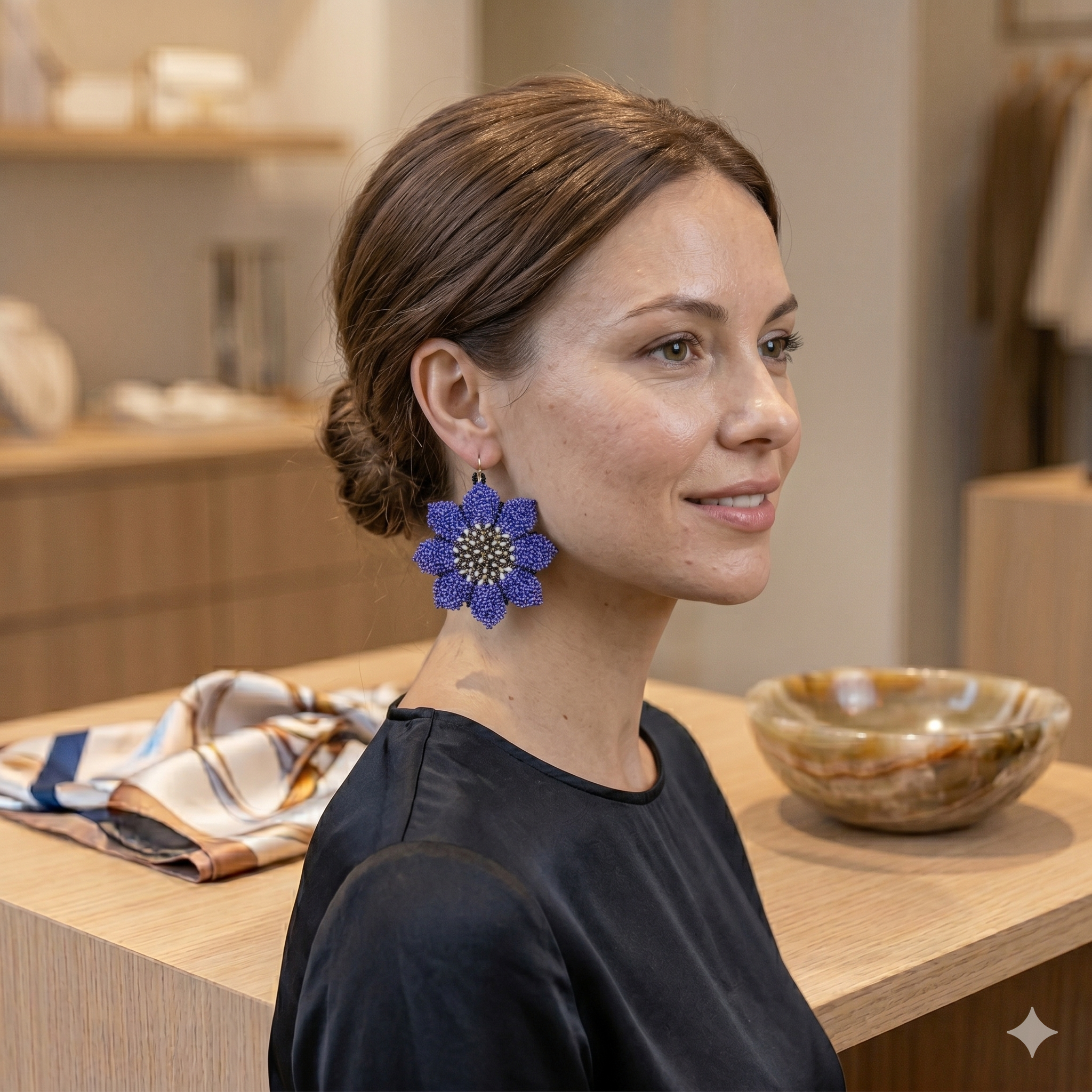 Gros plan de profil d'une femme souriante portant les boucles d'oreilles fleurs en perles bleues, mettant en valeur l'éclat du bijou.