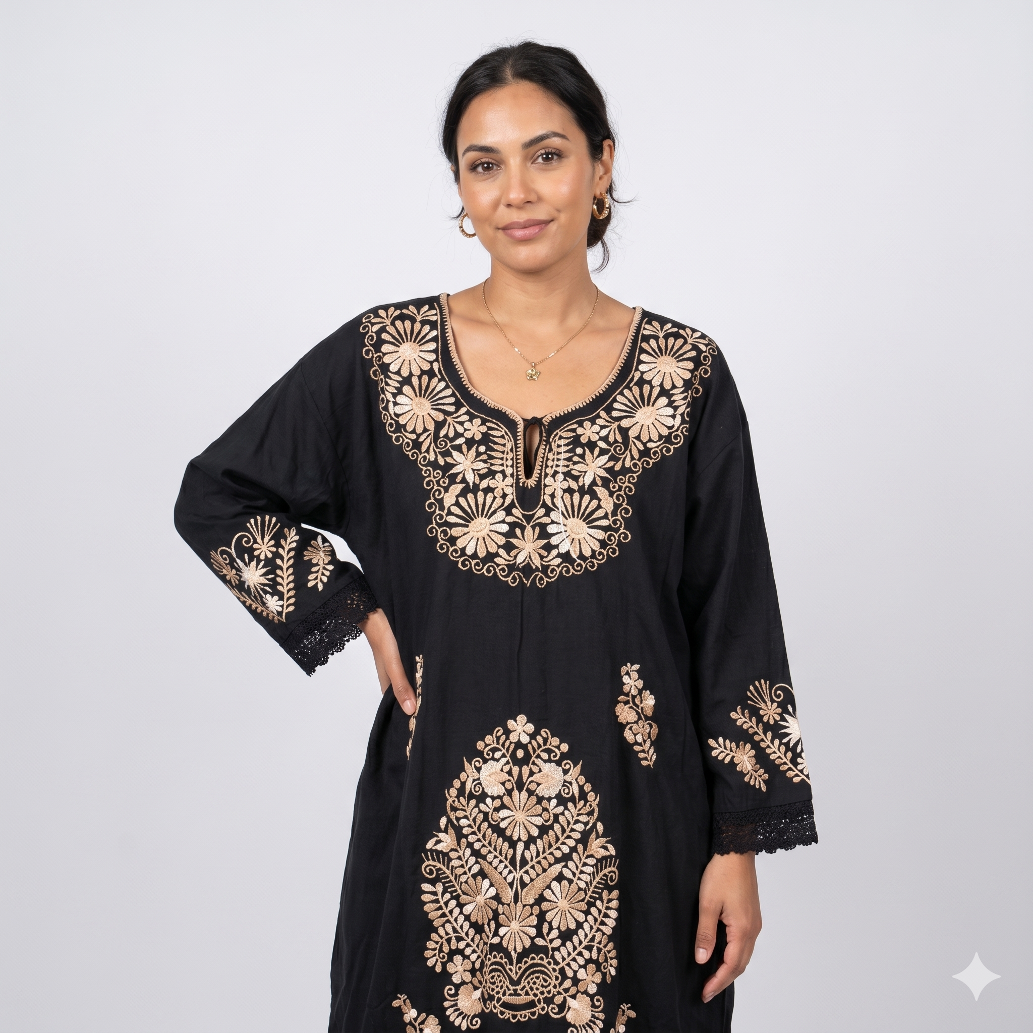 Femme aux cheveux bruns attachés portant une robe caftan noire avec broderies dorées au décolleté, coupe fluide et élégante pour une silhouette moderne.